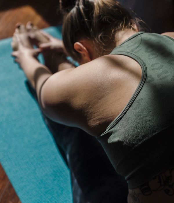 Woman in a calming yoga pose in a dimly lit room.